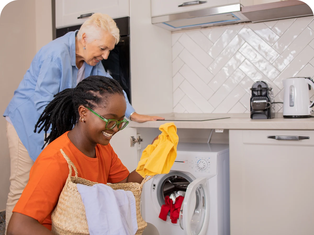 Two people doing laundry in kitchen.